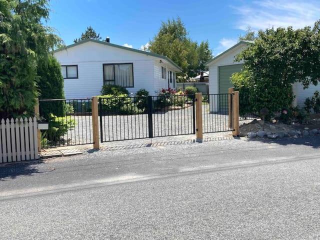 a wooden fence in front of a white house at Terrific house on totara drive in Twizel
