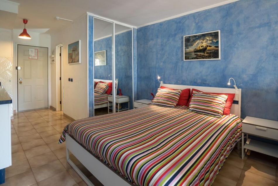 sypialnia z łóżkiem i niebieską ścianą w obiekcie Castle Margherita's Apartments w mieście Los Cristianos
