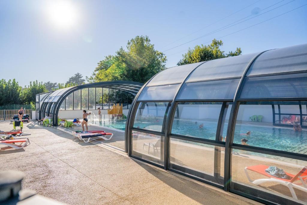uma piscina ao lado de um edifício de vidro com pessoas nele em Camping Harrobia em Bidart