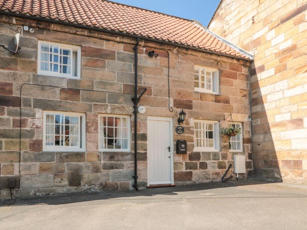 a brick building with a white door and windows at Stoney Cottage in Saltburn-by-the-Sea