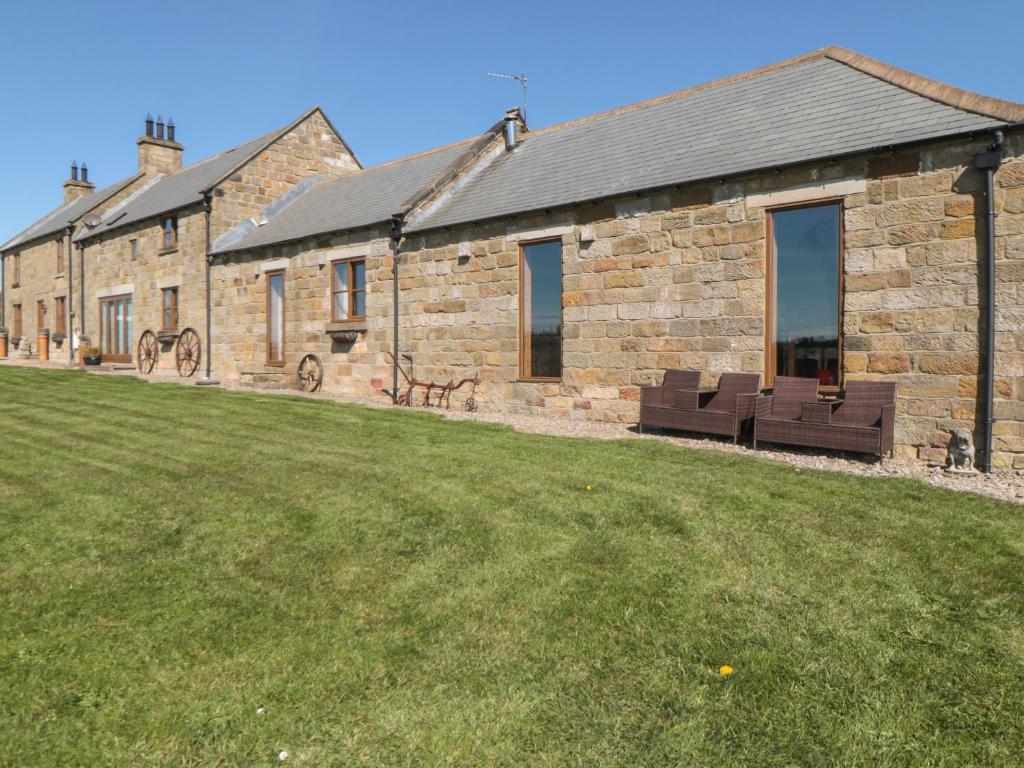 un edificio in mattoni con una panchina di fronte a un cortile di Longstone Cottage a Ugthorpe