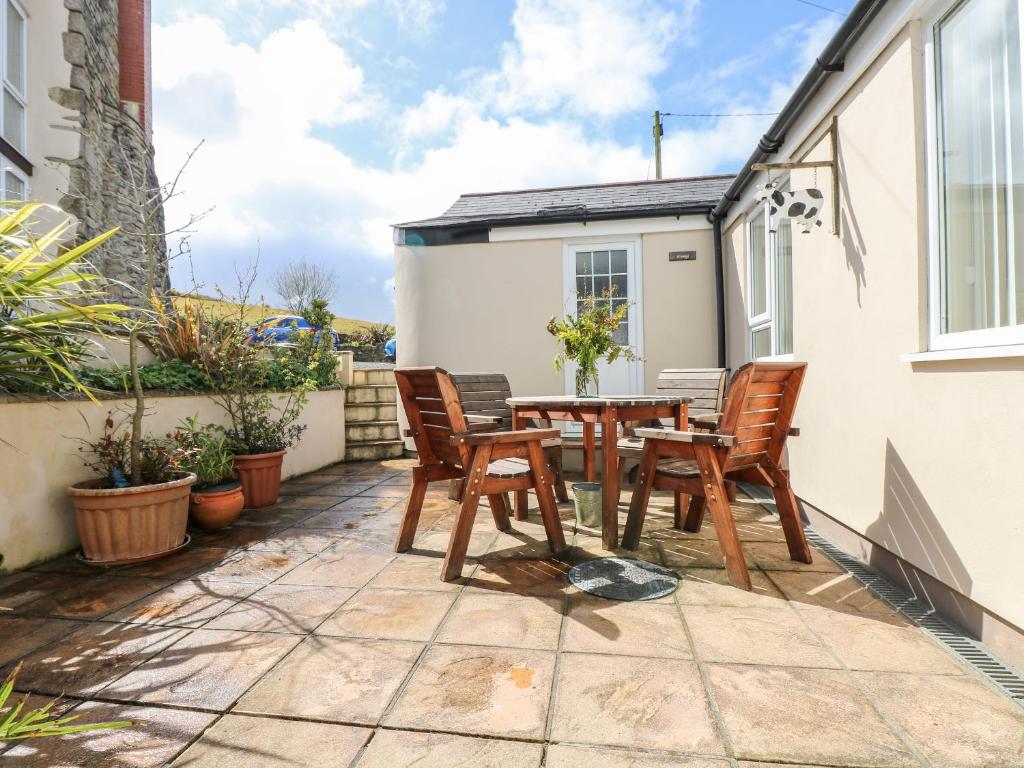 a patio with a wooden table and chairs at Mynheer Farm Bowji in Redruth