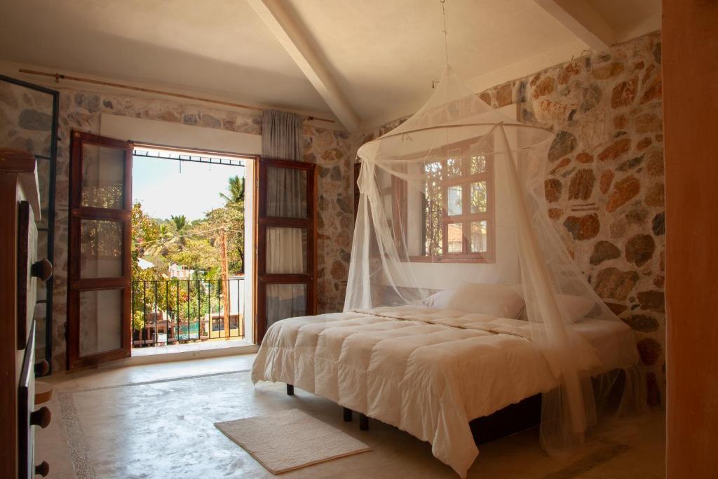 ein Schlafzimmer mit einem Himmelbett und einem Fenster in der Unterkunft M a r e a V i v a in Zipolite