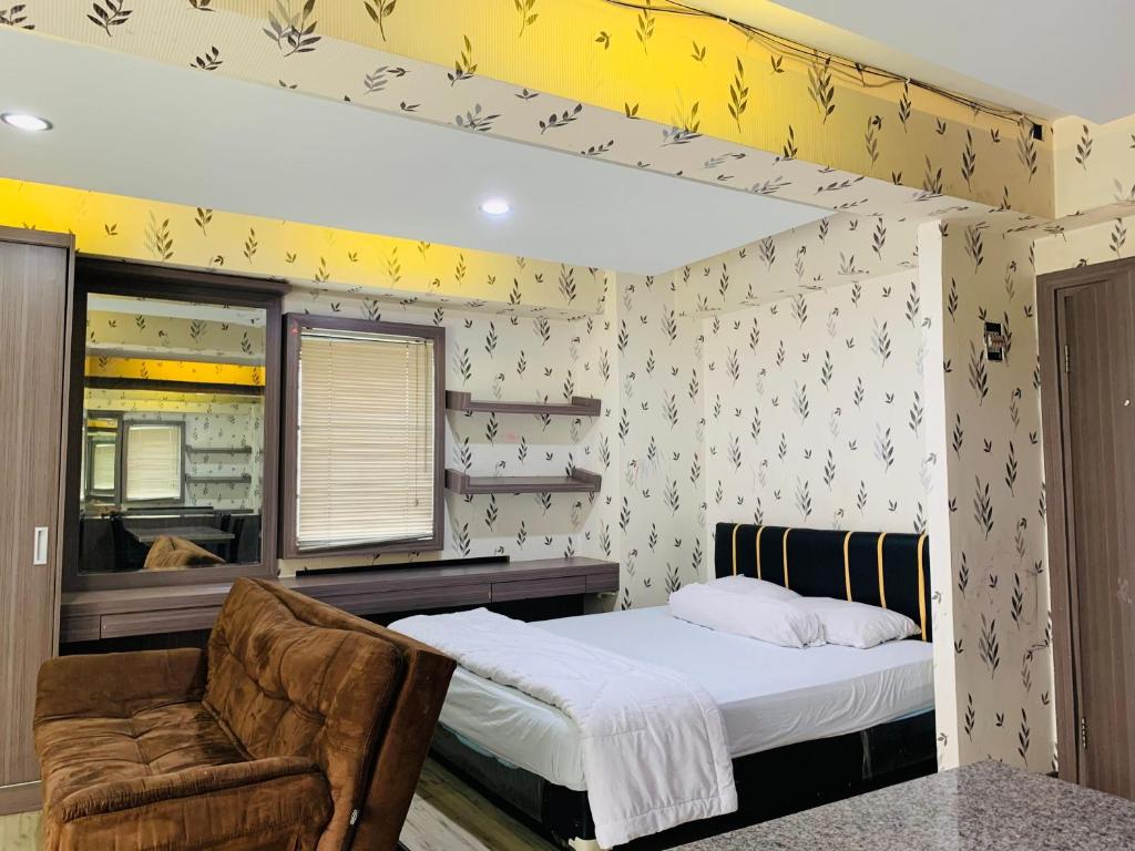 a bedroom with a bed and a chair at Apartemen Cibubur Village by Raja Sulaiman Property in Cibubur