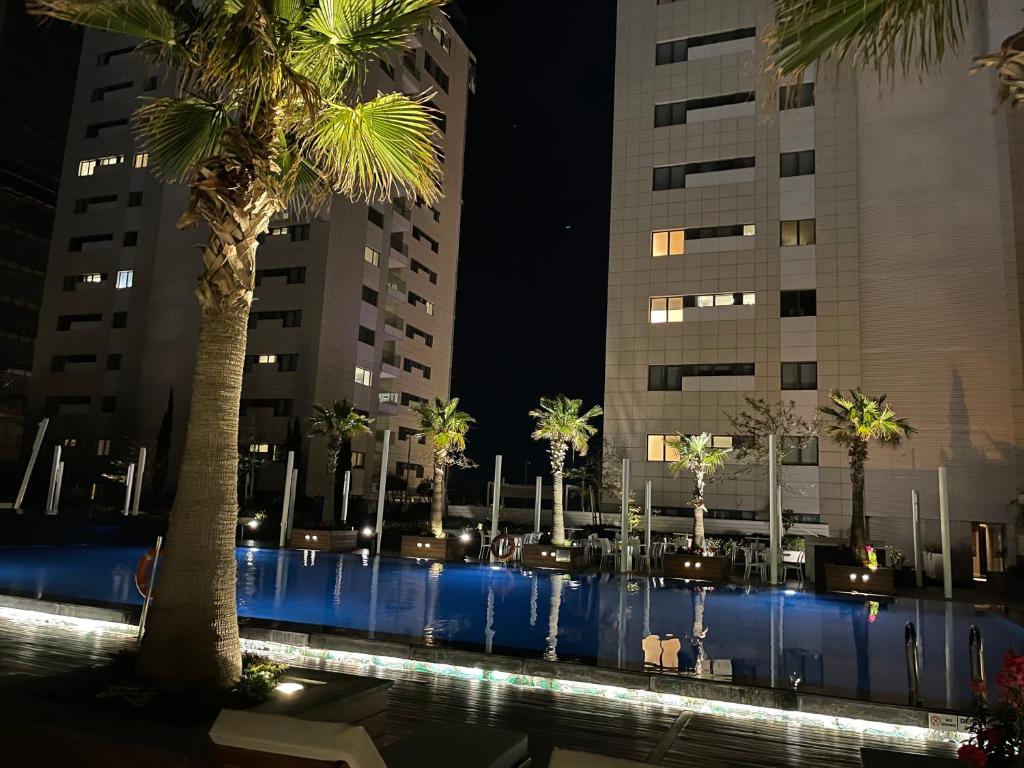 una piscina con palmeras y edificios por la noche en Olympic Residence Deluxe Apartments, en Limassol