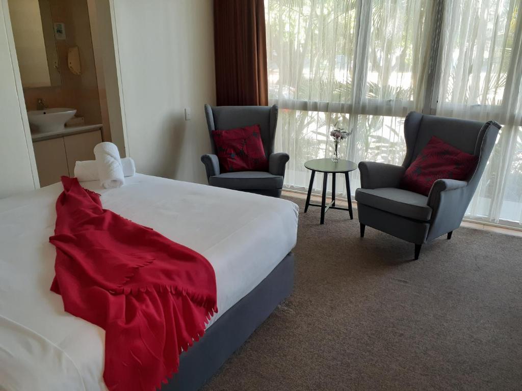 1 dormitorio con 1 cama, 2 sillas y mesa en City Star Lodge, en Brisbane