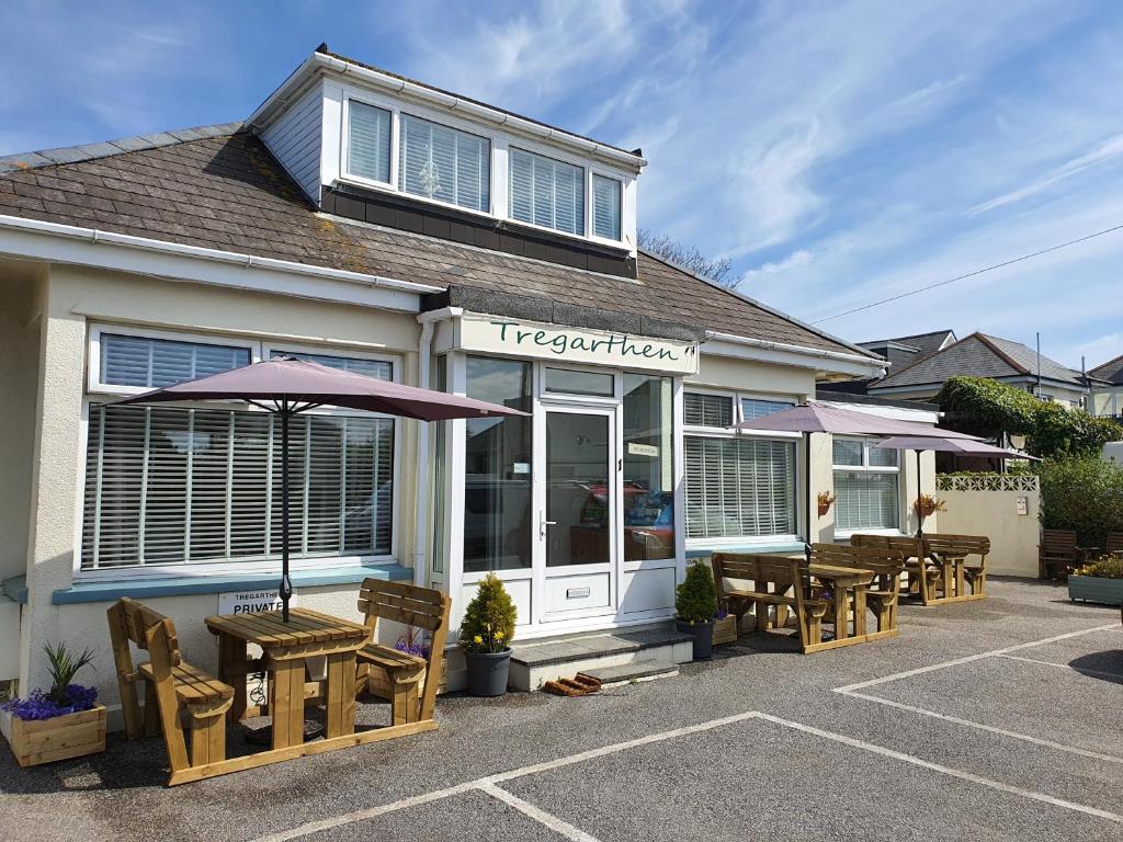 a restaurant with tables and umbrellas outside of it at Tregarthen - Adult Only in Newquay