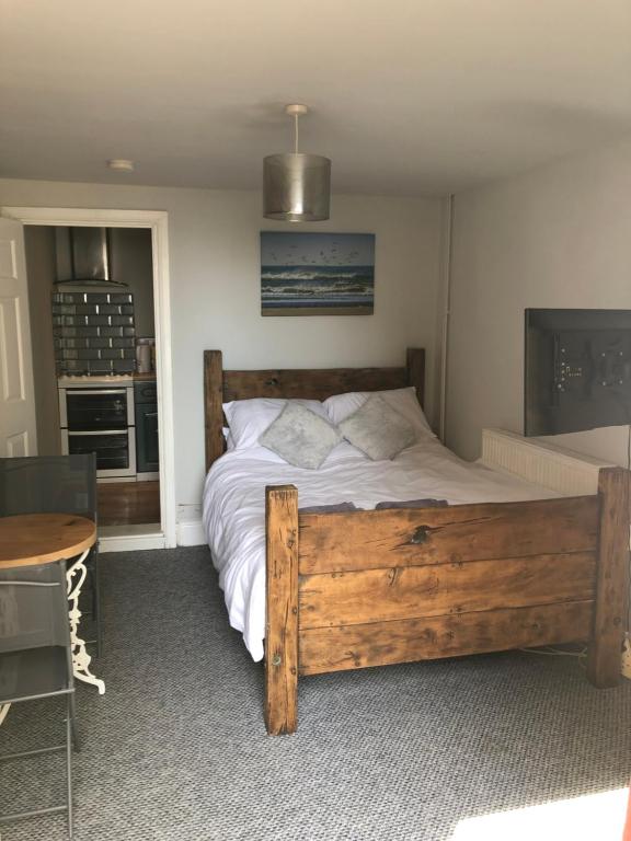 um quarto com uma grande cama de madeira e uma mesa em Sea view studio em Felixstowe