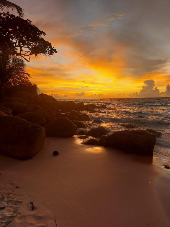 a sunset on a beach with rocks and the ocean at The Mantra Hotel Kata Noi in Kata Beach