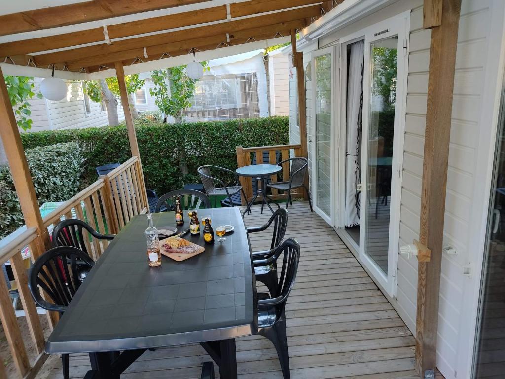 un patio con mesa y sillas en una terraza en Mobil-home climatisé à Valras Plage dans le camping 4 étoiles les Sables du midi à 800m de la plage en Sérignan