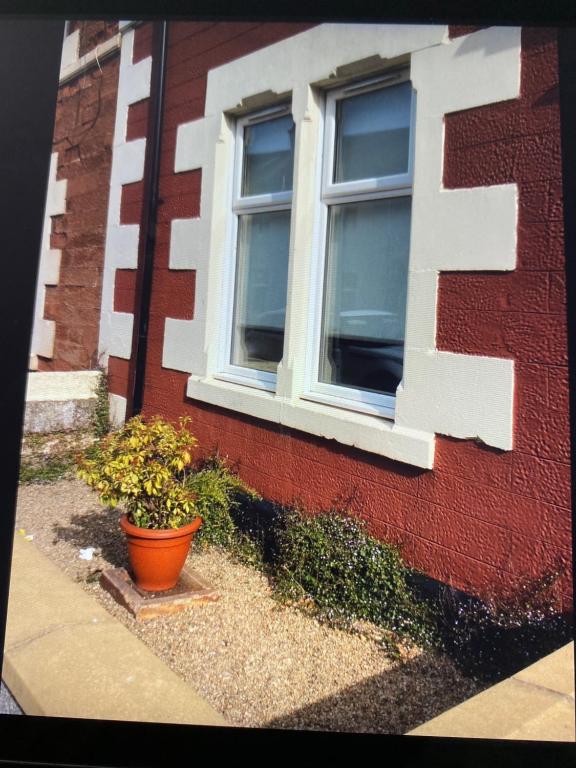 a red brick building with a window and a flower pot at Ground floor / L 103 Nelson street in Largs