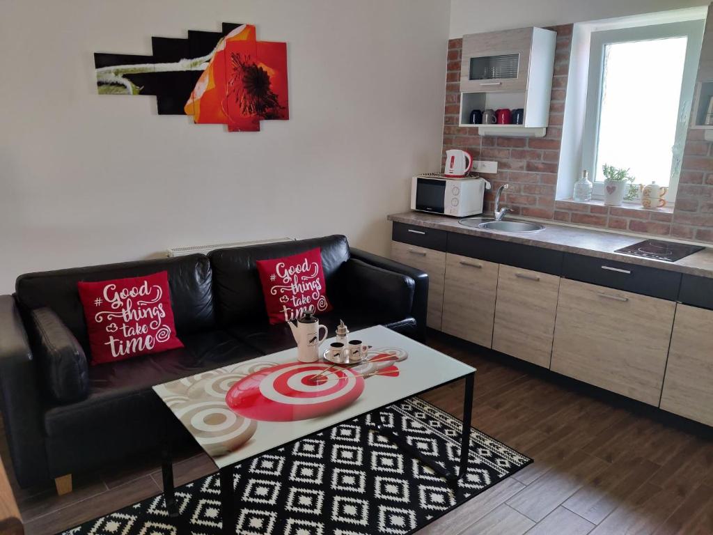 ein Wohnzimmer mit einem schwarzen Ledersofa und einem Tisch in der Unterkunft Apartman Biskupice in Fiľakovo