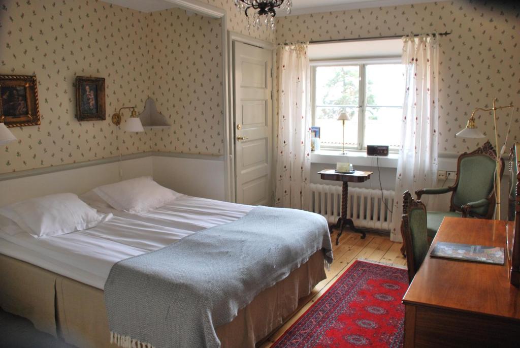 um quarto com uma cama, uma secretária e uma janela em Sigtunastiftelsen Hotell & Konferens em Sigtuna