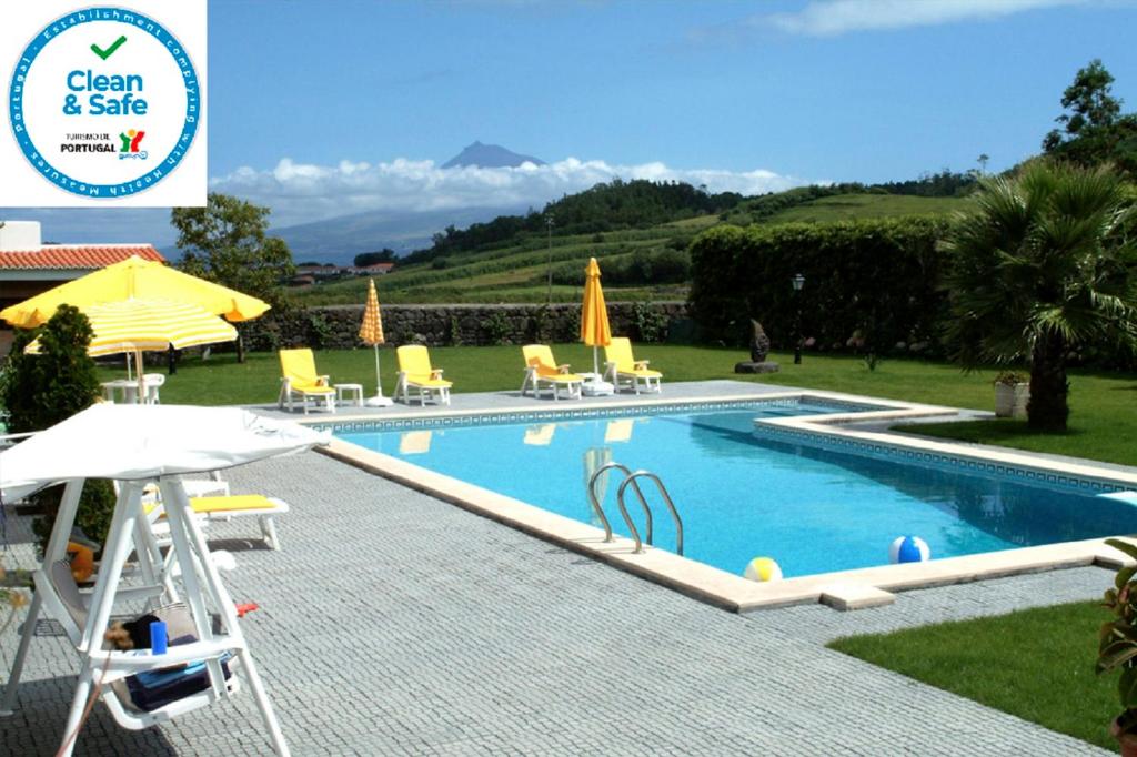a swimming pool with chairs and umbrellas in a yard at Quinta do Vale in Horta