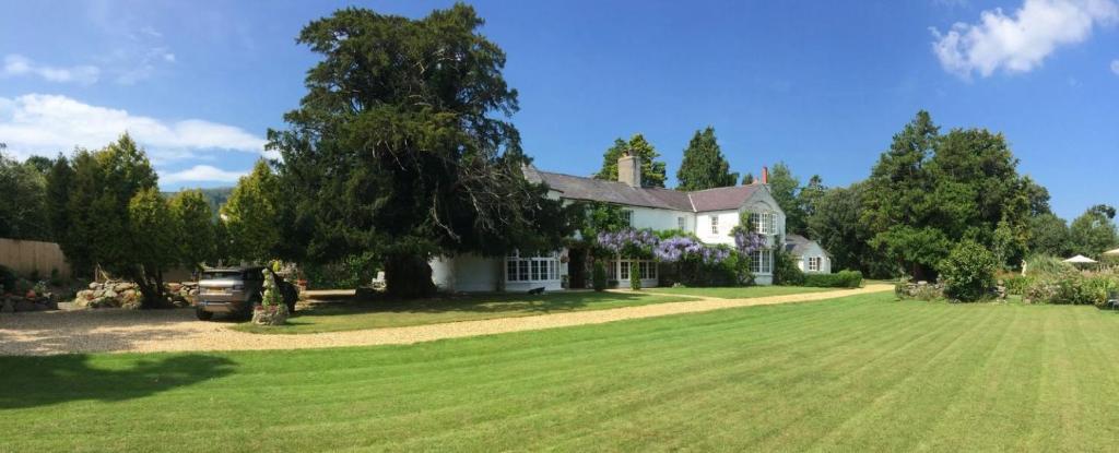 a white house with a large grass yard at Glyn Isa Country House B&B and self catering Lodge in Conwy