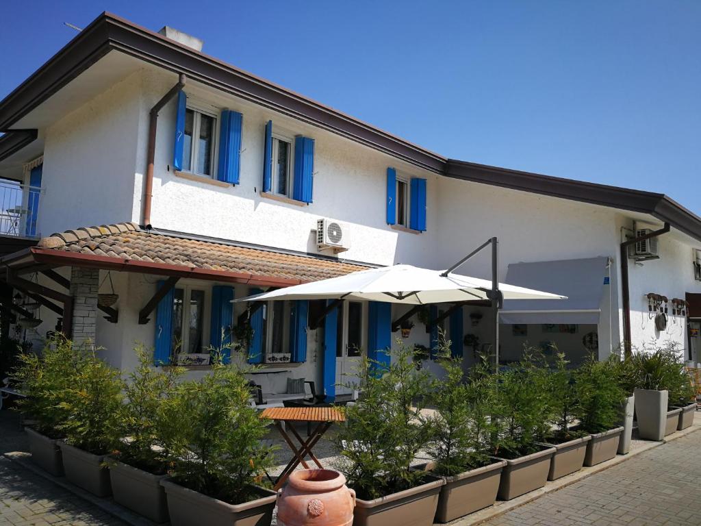 ein weißes Gebäude mit blauen Fenstern und einem Sonnenschirm in der Unterkunft Villa Roma Holidays in Jesolo
