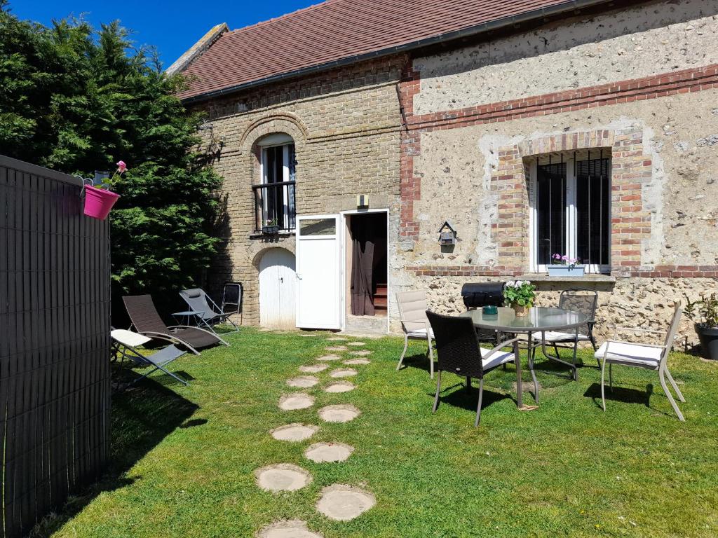 a yard with a table and chairs and a building at Gite De La Baguelande in Les Andelys