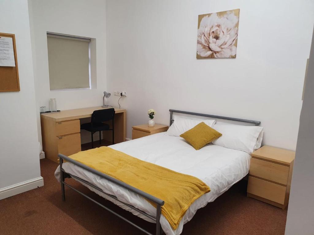 a bedroom with a bed with a yellow blanket on it at D19 SANGHA HALL in Leicester