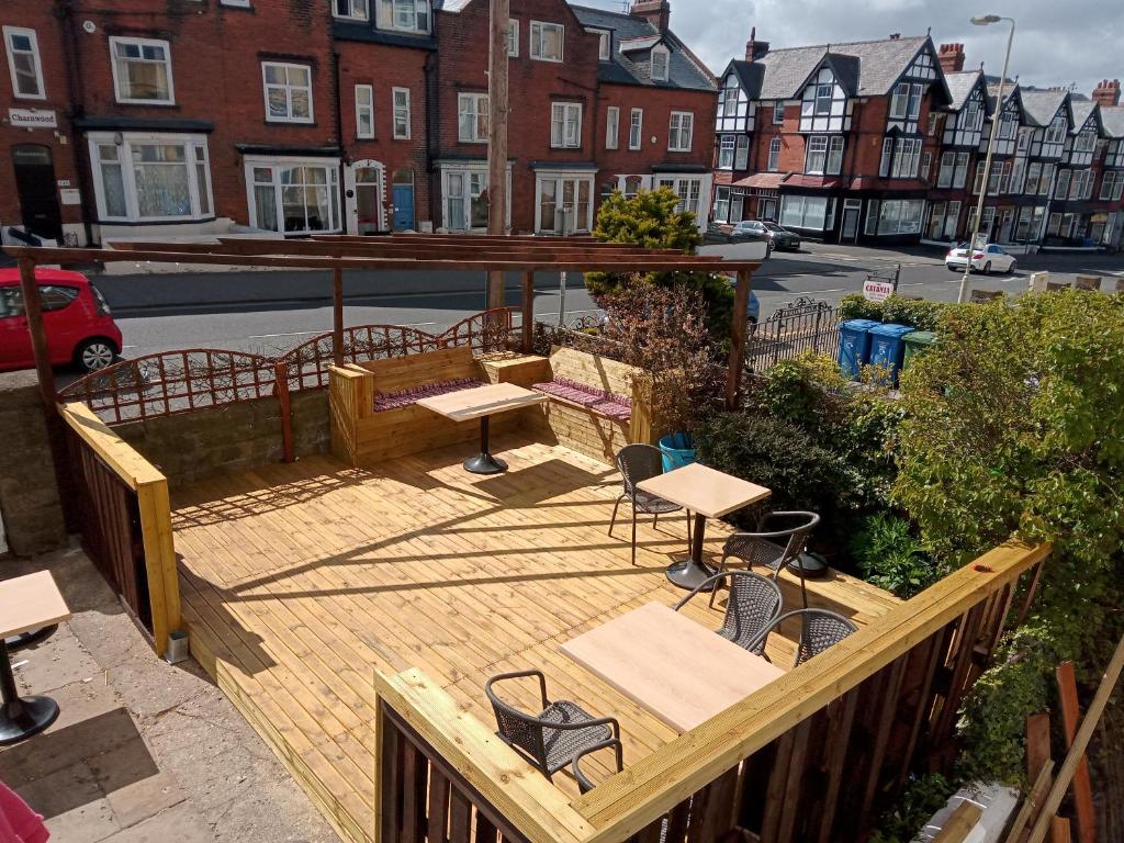 a wooden deck with tables and chairs on a street at The Kenton Hotel in Scarborough