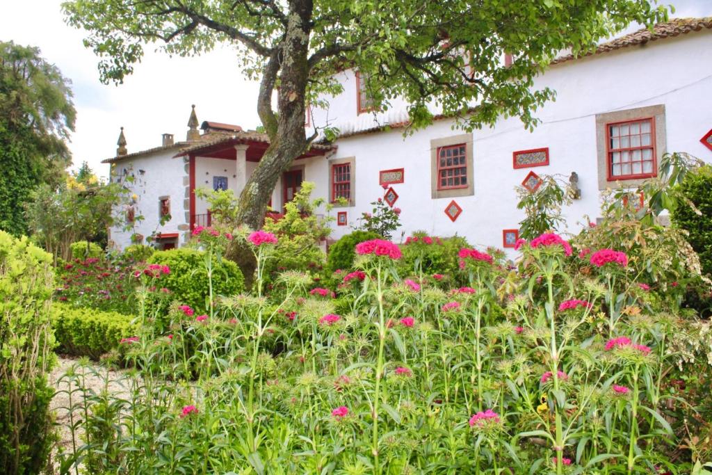 einen Garten vor einem weißen Haus mit rosa Blumen in der Unterkunft Quinta da Maínha - Charming Houses in Braga
