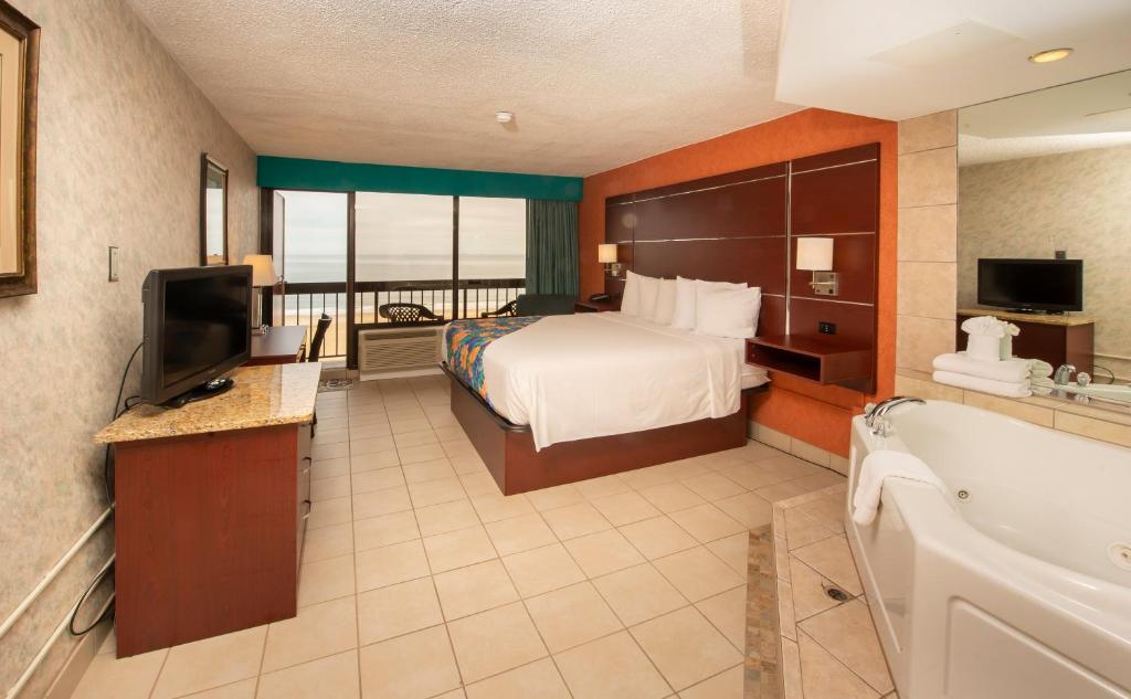 um quarto de hotel com uma cama e uma banheira e uma televisão em The Breakers Resort Inn em Virginia Beach