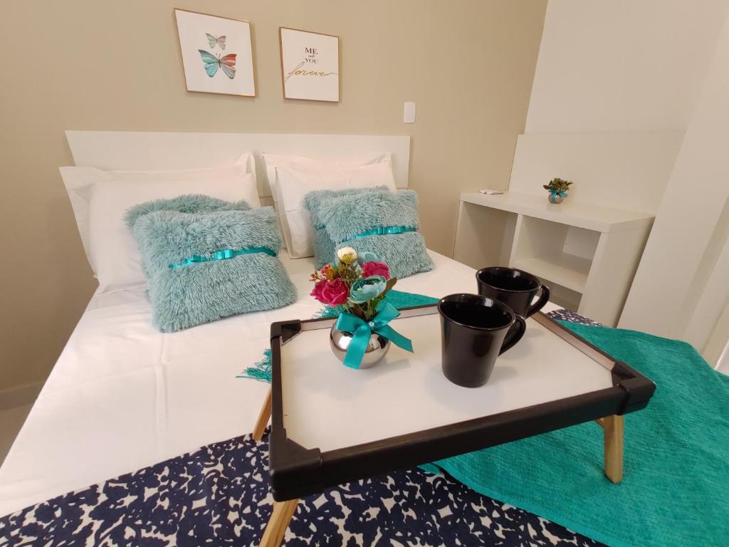 een slaapkamer met een bed met een tafel met bloemen erop bij Apto Estiloso Balneário Camboriú 200m da praia in Balneário Camboriú