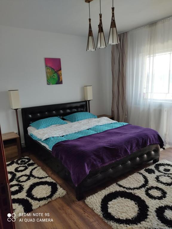 a bedroom with a bed with purple sheets and a rug at Apartment Farmec in Cluj-Napoca