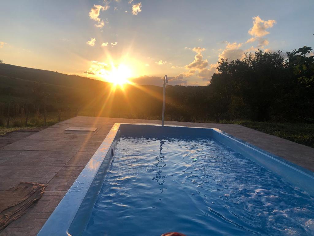 a swimming pool with the sun in the background at Sítio Tapera em Ibitipoca - MG, com Wi-Fi in Conceição da Ibitipoca