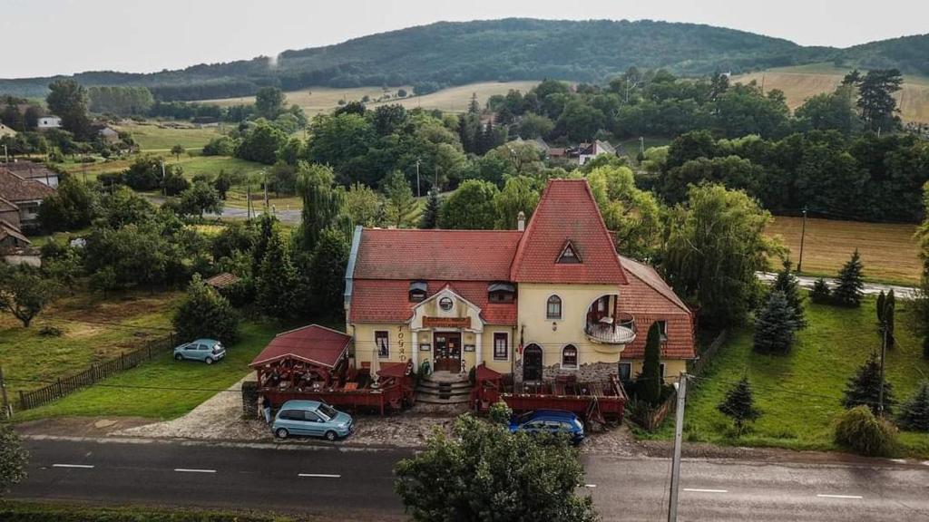 Cserhátvölgy Panzió في Alsótold: منزل كبير فيه سيارات متوقفة أمامه