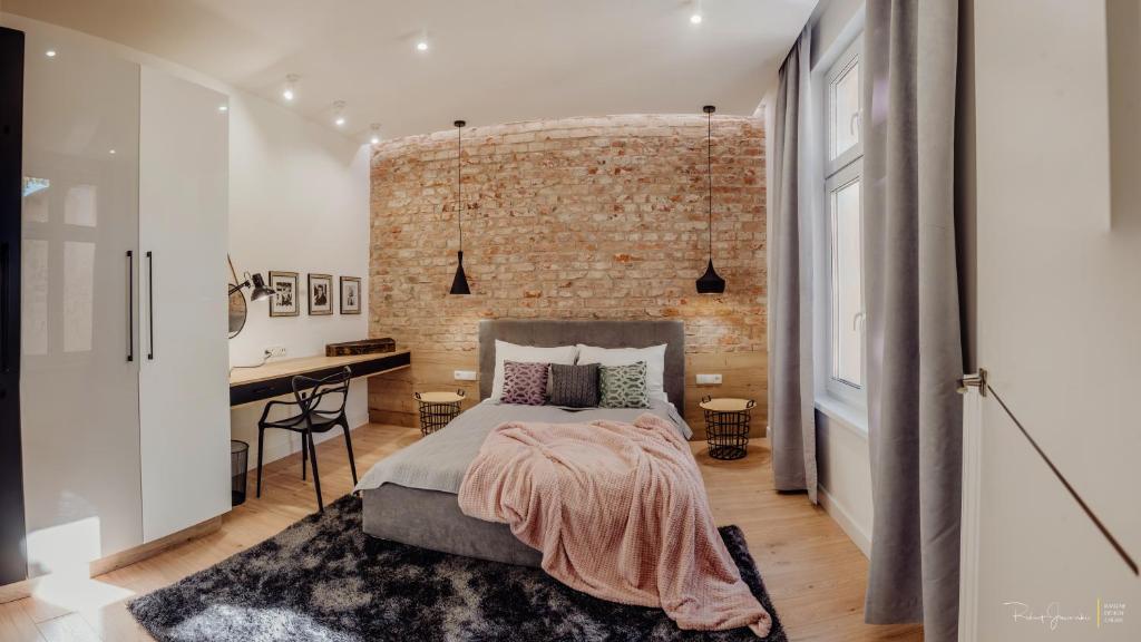 - une chambre avec un mur en briques, un lit et un bureau dans l'établissement Apartament LUX Cieplice, à Jelenia Góra