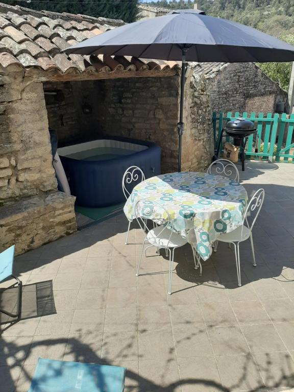 a table and chairs under an umbrella on a patio at Gite au cœur du Luberon in Goult
