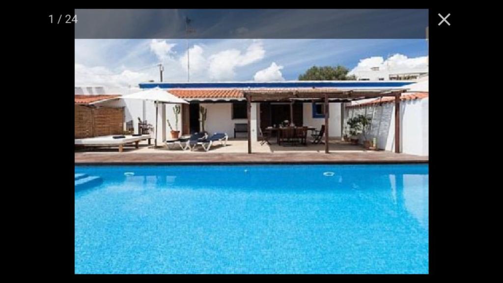 une grande piscine bleue en face d'une maison dans l'établissement Can Ballet, à Ibiza