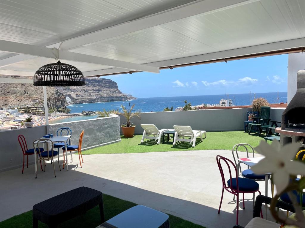 a patio with chairs and tables and a view of the ocean at Pensión Playa in Puerto de Mogán