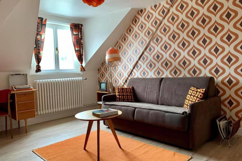uma sala de estar com um sofá e uma mesa em Appartement Vintage avec vue sur le château em Pierrefonds