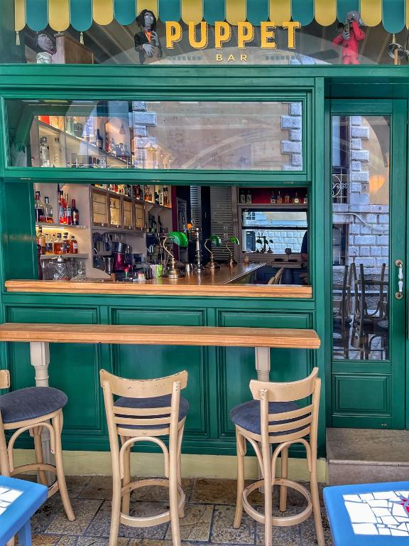 a green bar with two chairs in front of it at Puppet rooms in Corfu
