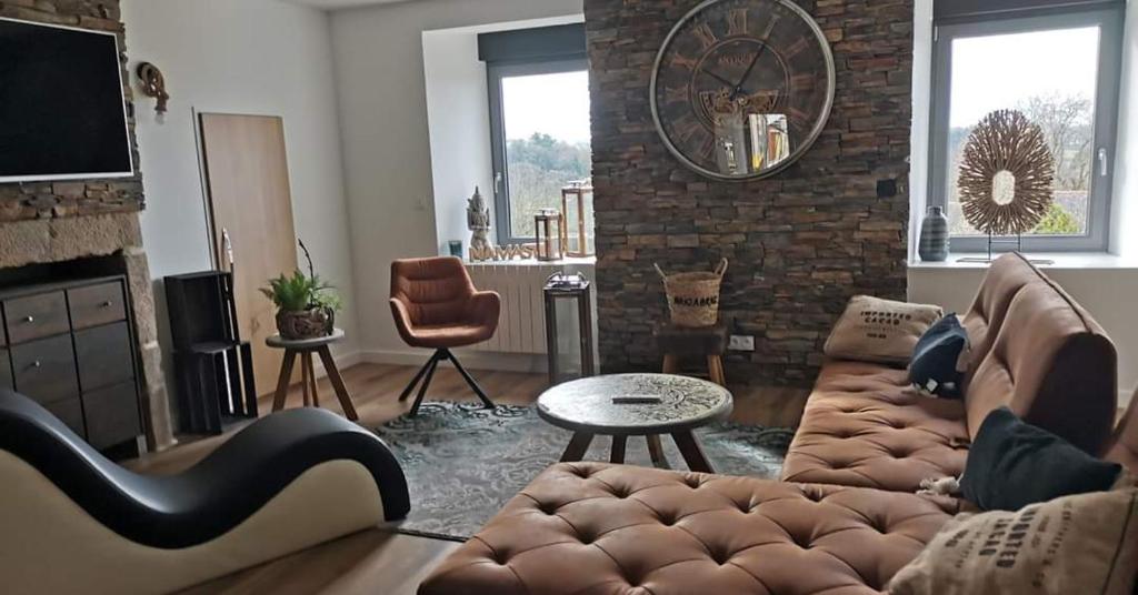 a living room with a couch and a clock on the wall at Loft 100m2 neuf entièrement équipée in Callac