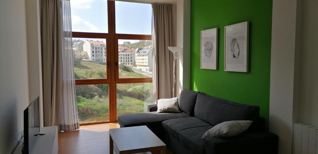 a green living room with a couch and a window at Apartamento Malpica de Bergantiños in Malpica