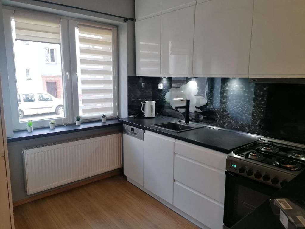 a kitchen with white cabinets and a sink and a window at Apartament Przy Kortach in Bytom