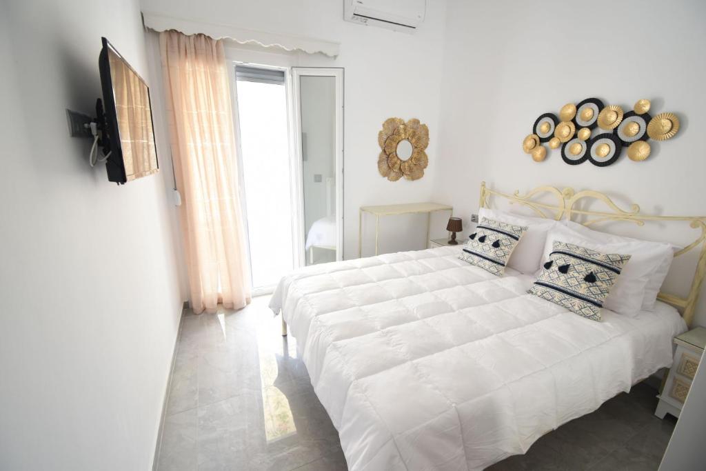 1 dormitorio blanco con 1 cama blanca grande con almohadas en Foivos Apartment, en Naxos Chora