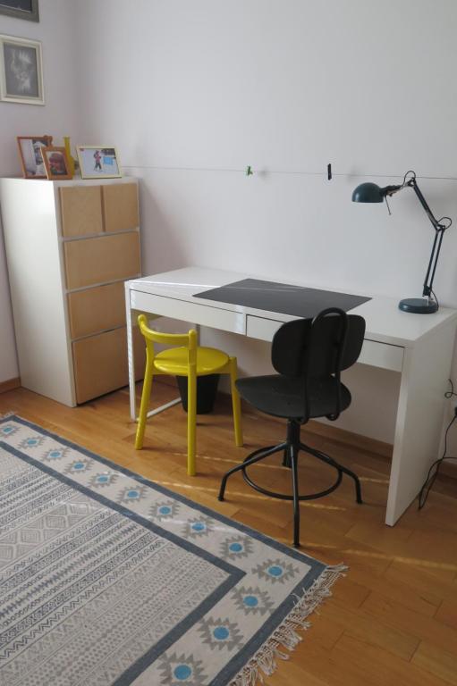 einen Schreibtisch mit einem gelben Stuhl und einen Schreibtisch mit einer Lampe in der Unterkunft Apartament Prusa in Bad Salzbrunn