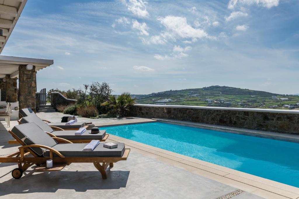 una piscina con tumbonas junto a una casa en Profitis Ilias Spirit Villas by Live&Travel, en Panormos  Mykonos