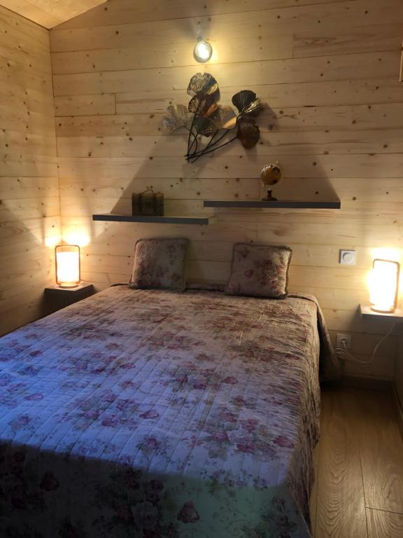 a bedroom with a bed with two lights on the wall at Fanjeaux Aude Le Chalet in Fanjeaux