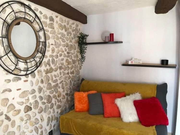 a living room with a couch with colorful pillows at Entre lac et lavandes in Roumoules