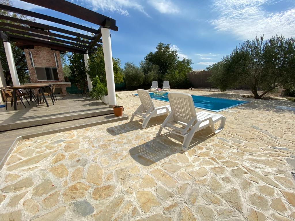 Duas cadeiras num pátio ao lado de uma piscina em Villa Bubica- cozy holiday home in rural area with pool em Stankovci