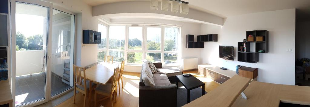 ein Wohnzimmer mit einem Tisch und einem großen Fenster in der Unterkunft ParkView Apartment in Danzig