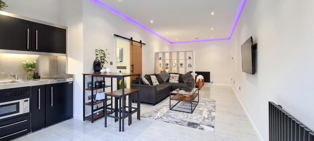 a living room with a couch and a kitchen at The Studio, Luxury Modern Apartment in The South Hams, Stunning walks on the doorstep, a 20 minute drive to the beautiful sandy beaches, quiet courtyard setting, Shops, Bars and Restaurants a short walk away! in Ivybridge