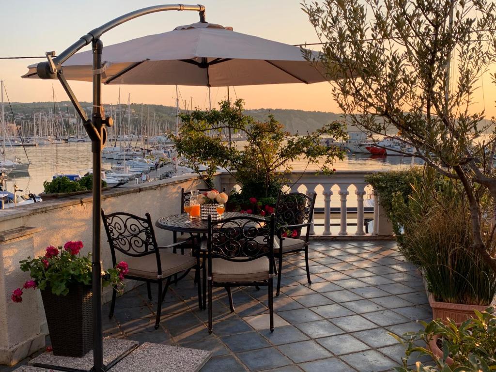 einen Tisch und Stühle unter einem Sonnenschirm auf dem Balkon in der Unterkunft First row to the sea - Maremi Izola Apartment terrace in Izola