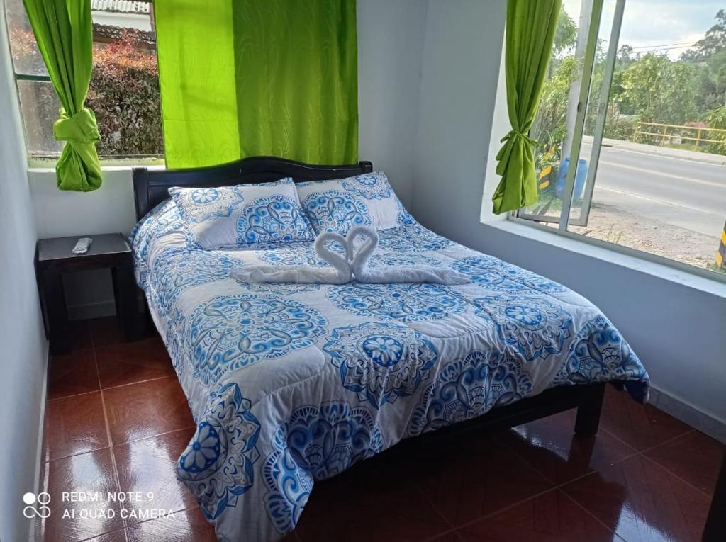 ein Bett mit einer blauen und weißen Bettdecke und einem Fenster in der Unterkunft Casa Campesina La Fagua in La Calera