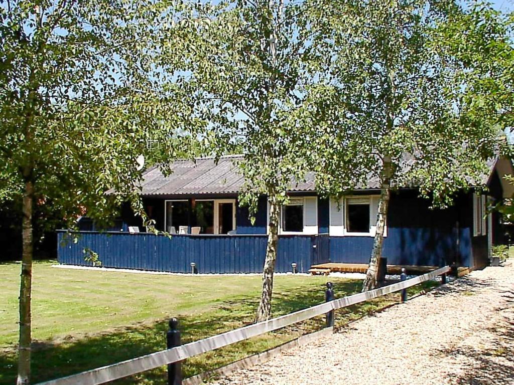 a blue house with a fence in front of it at 6 person holiday home in Hemmet in Falen