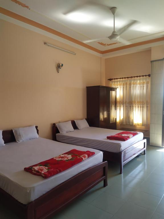 a bedroom with two beds with red sheets at Nhà Nghỉ Minh Quân in Ha Tien